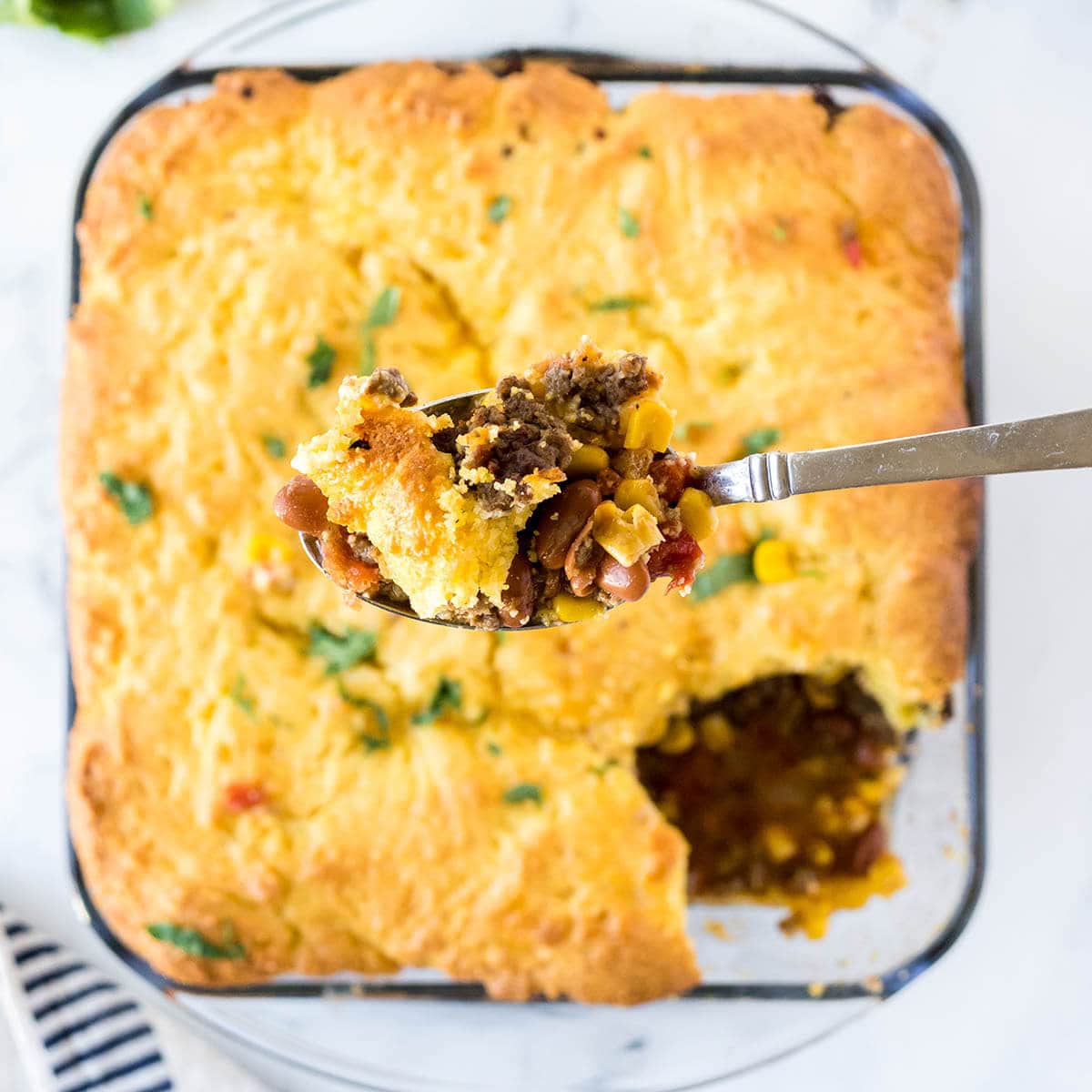 Cowboy Cornbread casserole in baking dish with serving spoon.