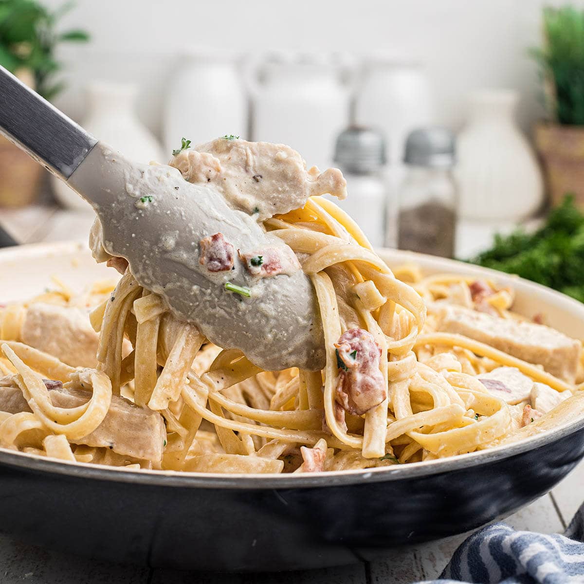 Cream Chicken and Bacon Pasta in a skillet with a serving utensil.