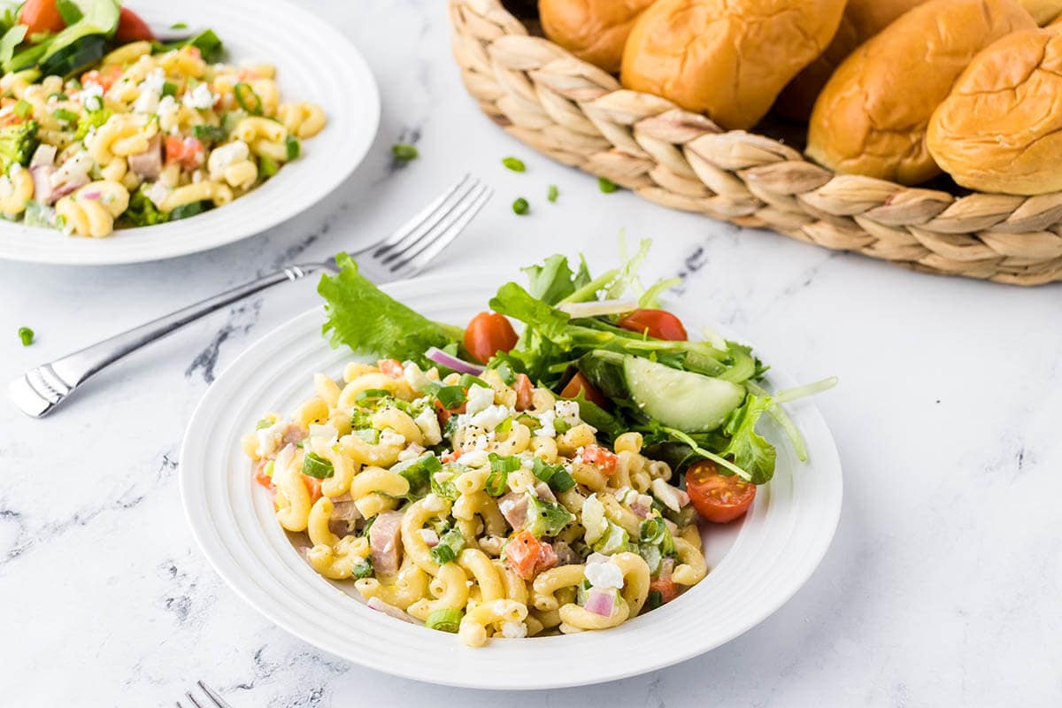 Plates filled with ham pasta salad and green salad.