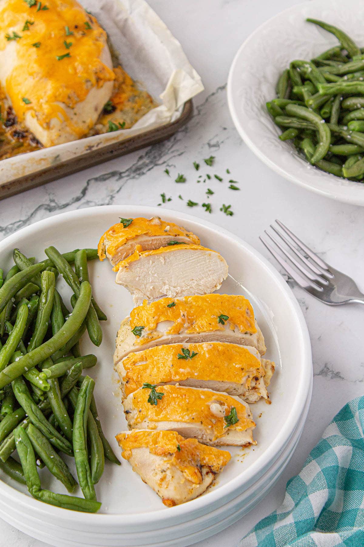 Cheesy ranch chicken on plate with green beans.
