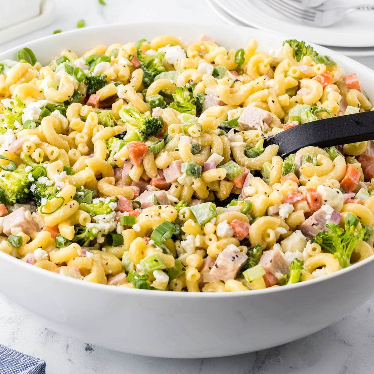 Large bowl of macaroni salad with serving spoon.