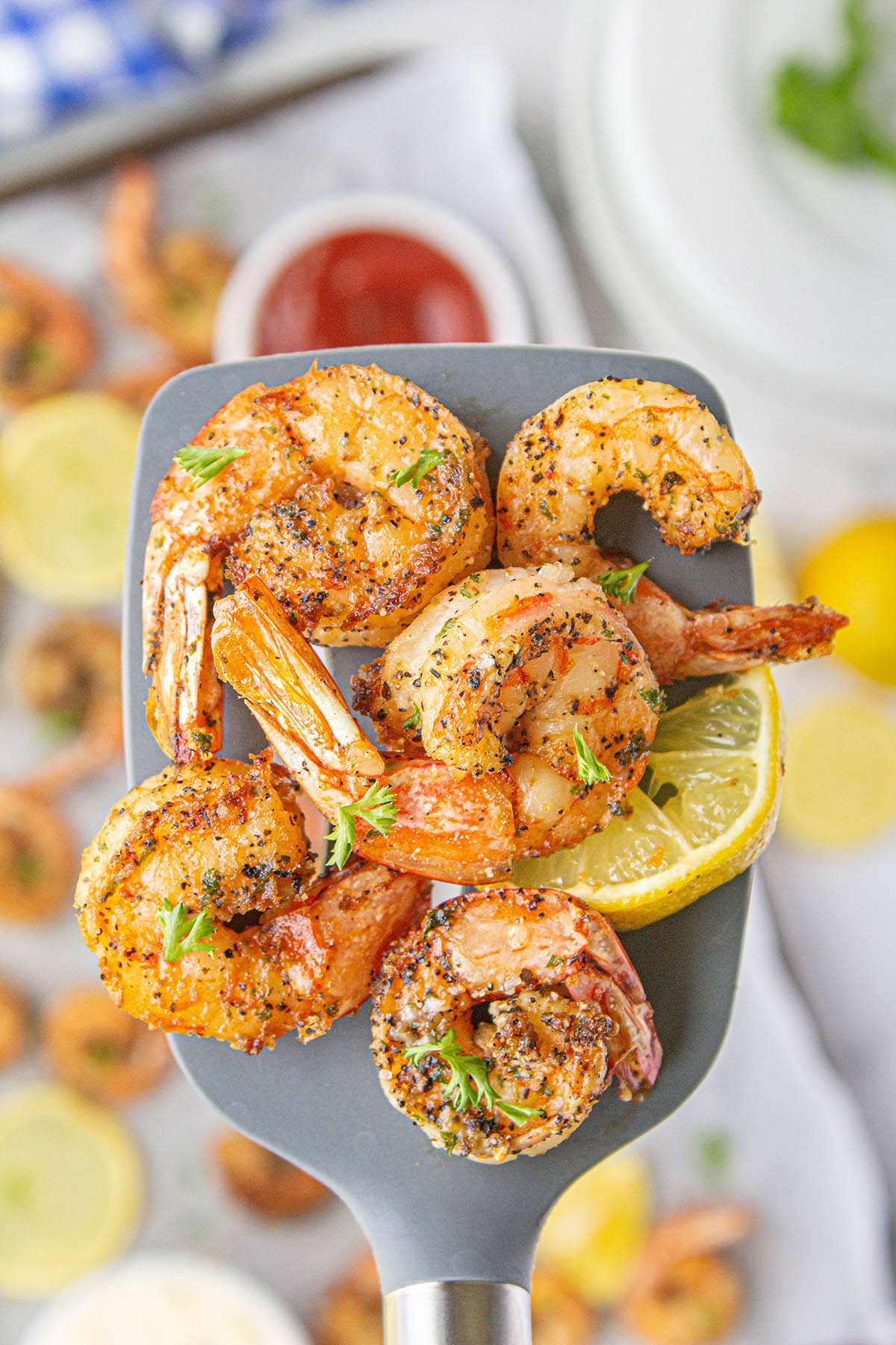 Spatula scooping up a serving of cooked shrimp.