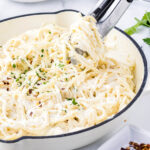 Cream cheese pasta recipe in pan with serving tongs.