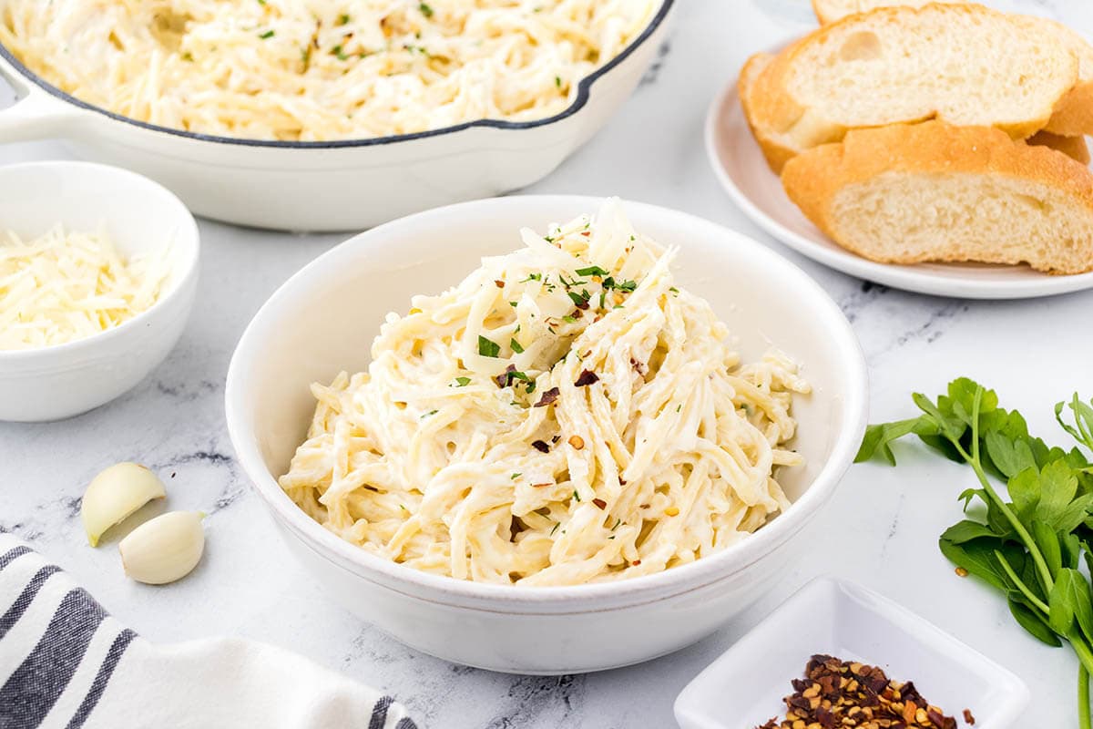 Bowls of pasta with bread on the side.
