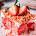 Slice of Strawberry Crunch Cake on plate topped with fresh strawberries.