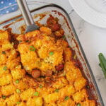 Chili Dog Tater Tot Casserole in a baking dish with a serving spoon.