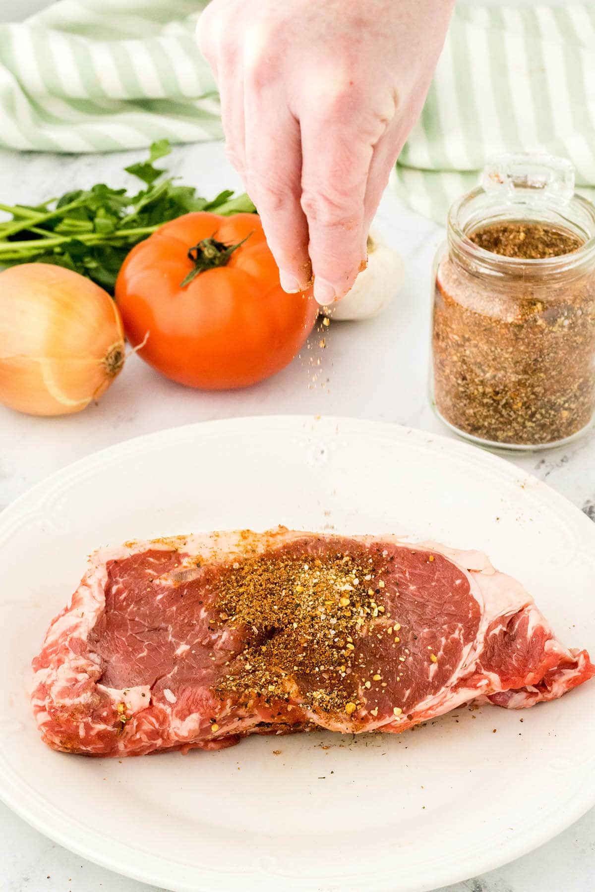 Steak on platter being seasoned.