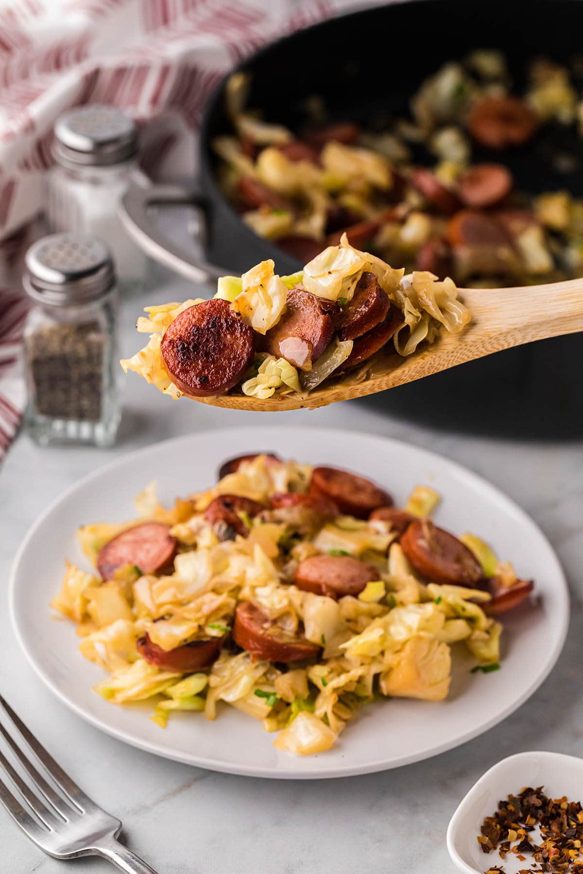 Kielbasa and cabbage on a plate with serving spoon.