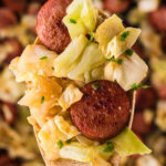 Kielbasa and Cabbage in cast iron skillet with a serving spoon. With print overlay.