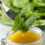 Salad Vinaigrette in jar with fork dipping greens into dressing.