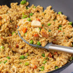 Chicken fried rice in wok with spoon.