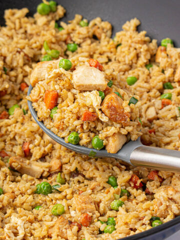 Chicken fried rice in wok with spoon.