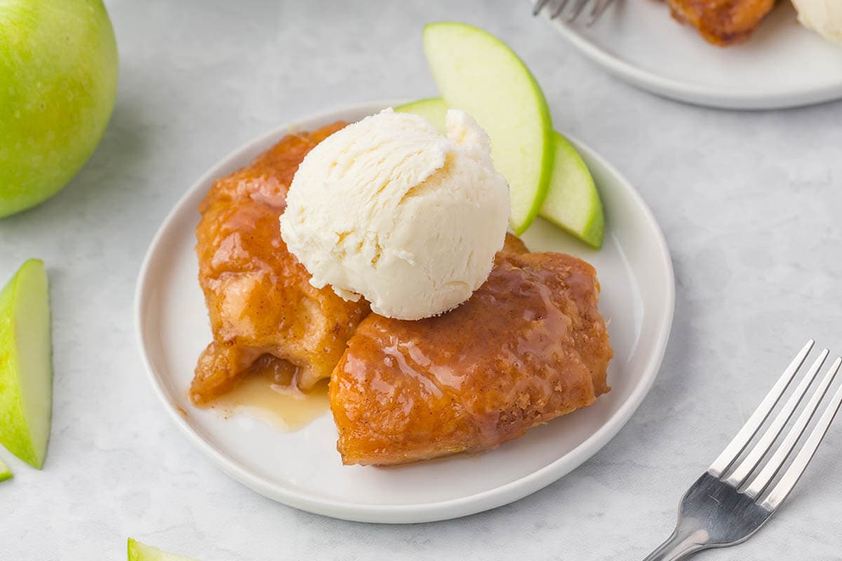 Apple Dumplings on a plate topped with vanilla ice cream.