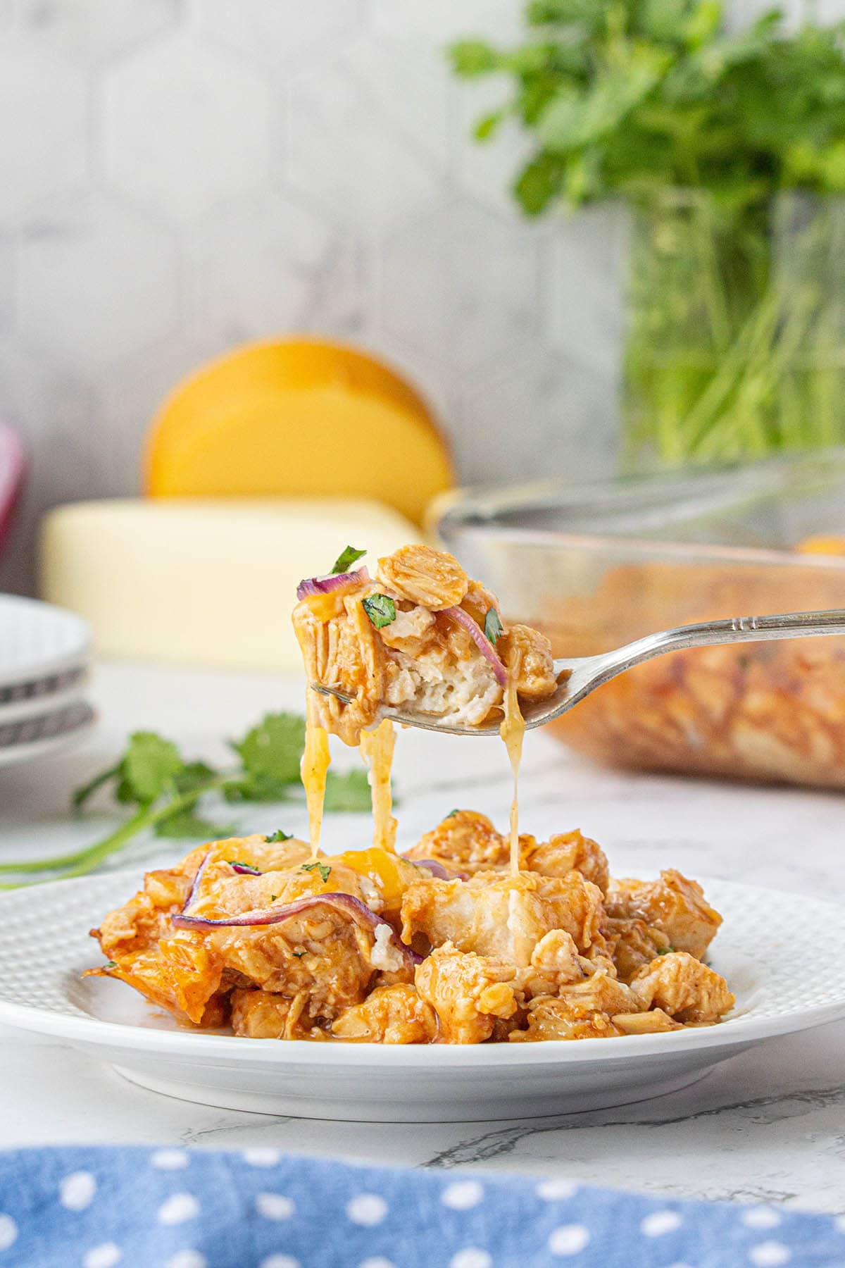 Plate with bbq chicken casserole with a fork filled and dripping with cheesy chicken.