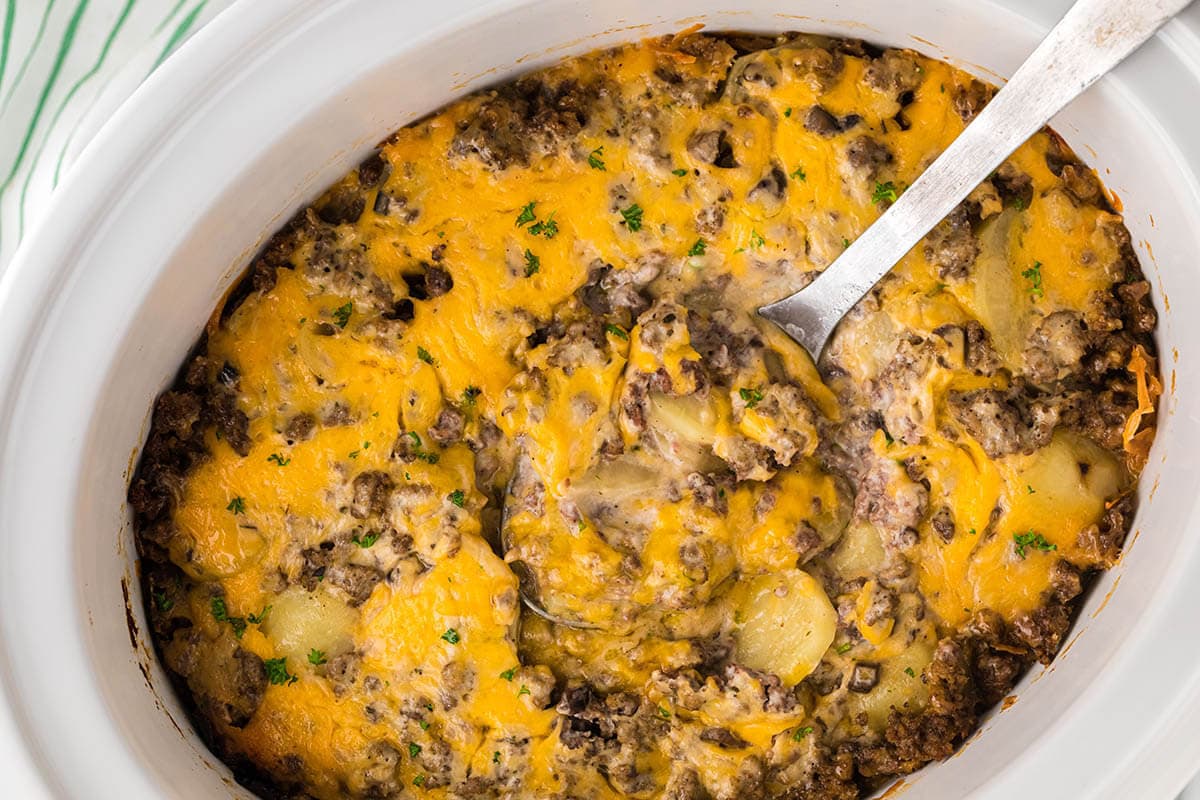 Crockpot Hamburger Potato Casserole in slow cooker with serving spoon.