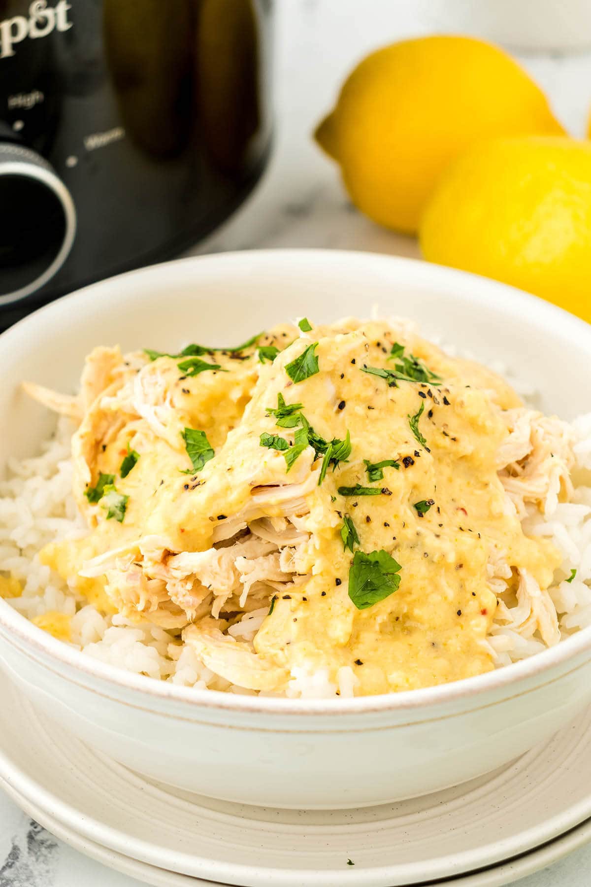 Slow Cooker Lemon Pepper Chicken over rice in a bowl.
