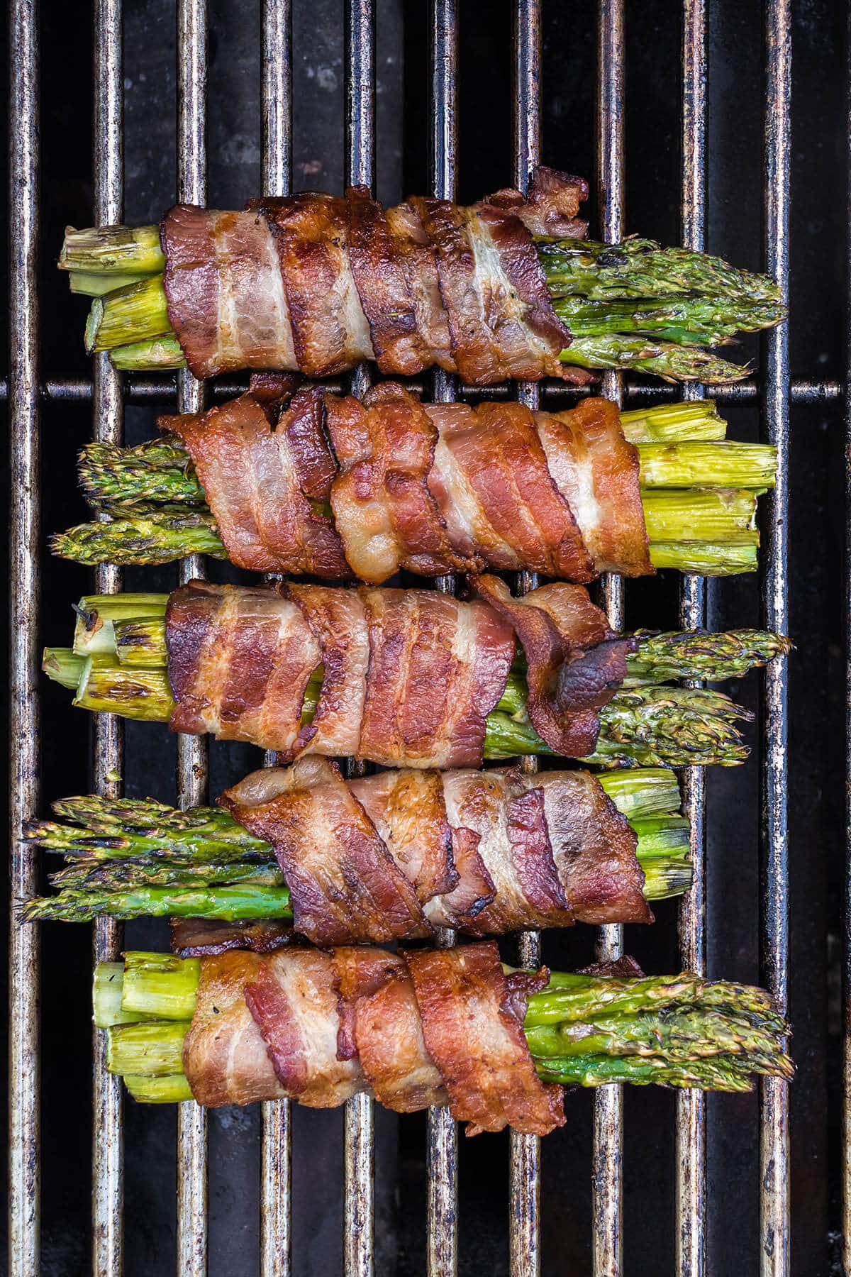 Bundles of cooked asparagus wrapped in bacon on the bbq.