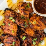 Hawaiian BBQ Chicken on a white platter surround by grilled pineapple rings. With print overlay for social media.