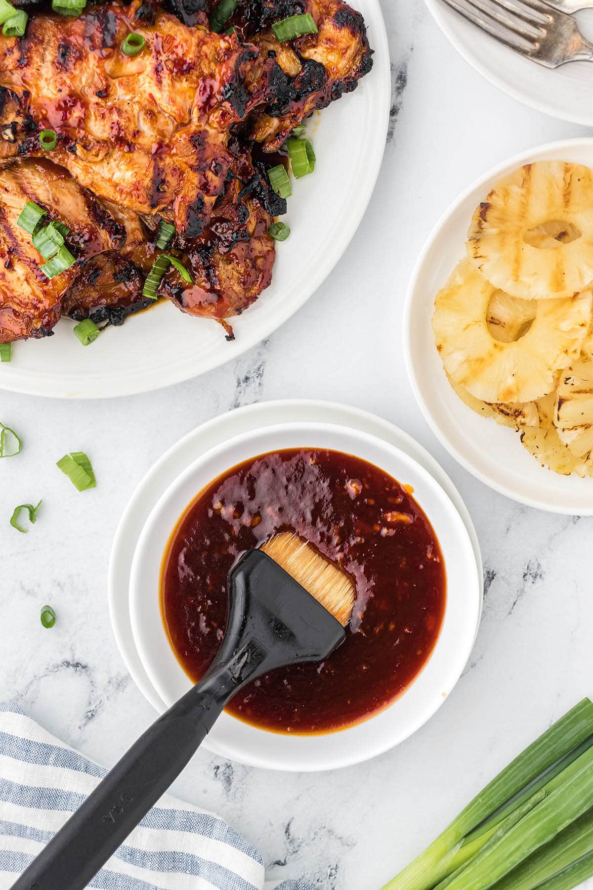 A white bowl filled with huli huli bbq sauce with bbq brush.