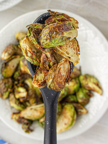 Serving spoon filled with air-fried brussels sprouts.