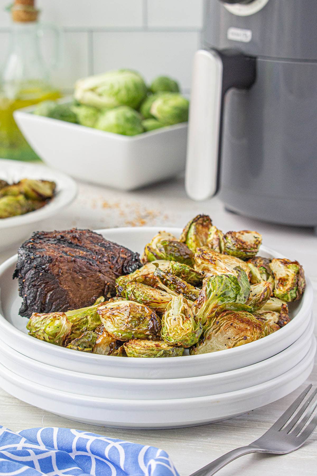 Air Fryer Brussels Sprouts on white plate with a steak.