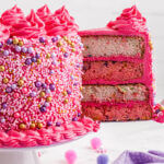 Pink and white funfetti layer cake with a slice being removed from the cake.
