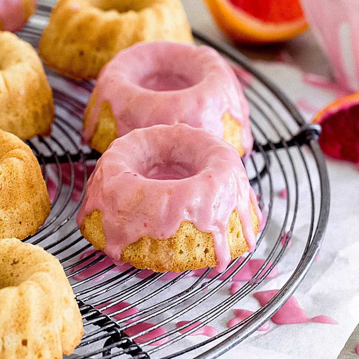 Mini Bundt Cakes on cooling rack topped with pink icing.
