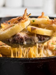 Ground Beef Casserole in a cast iron skillet with a spoon taking out a big scoop.