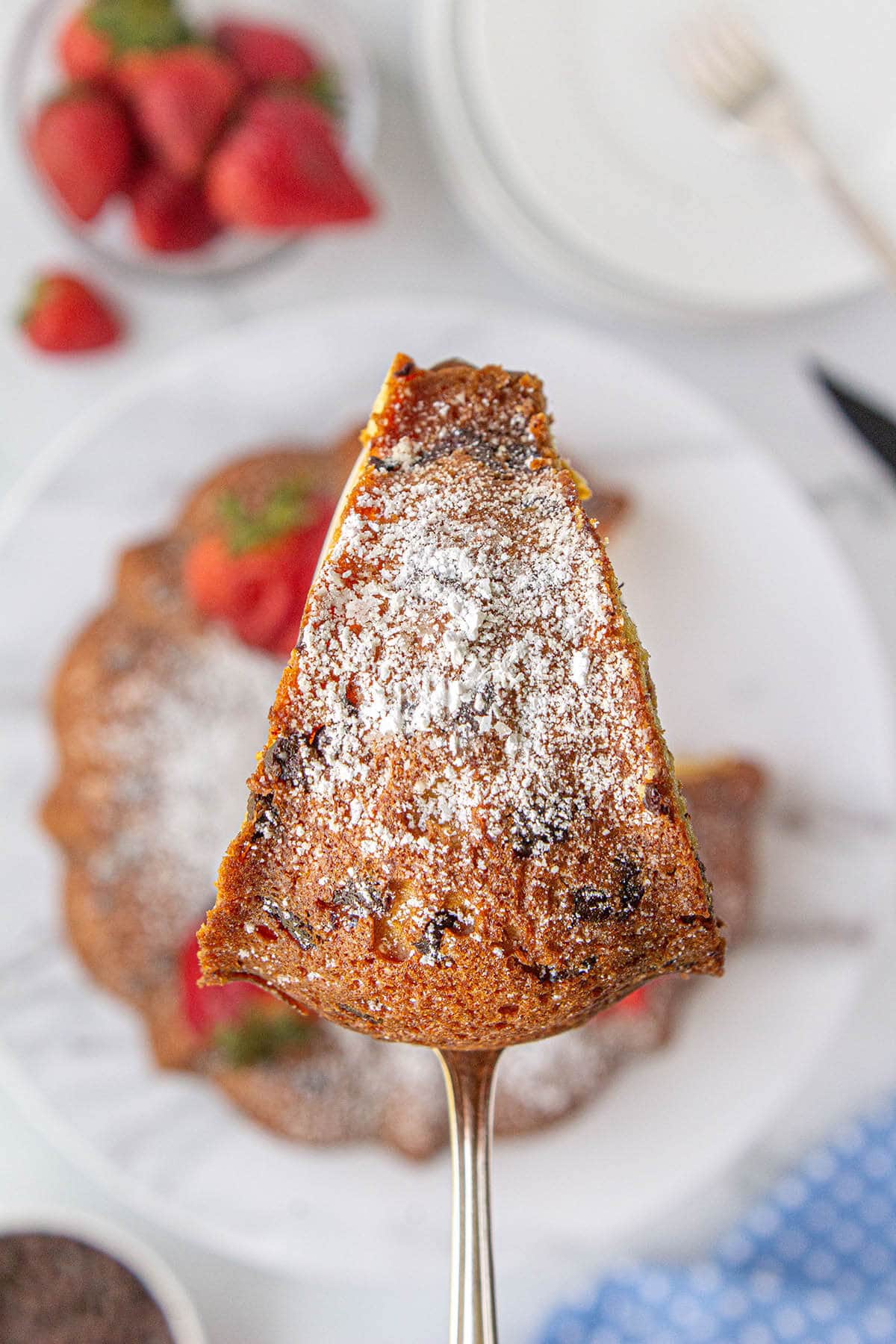 Slice of cake on spatula topped with powdered sugar.