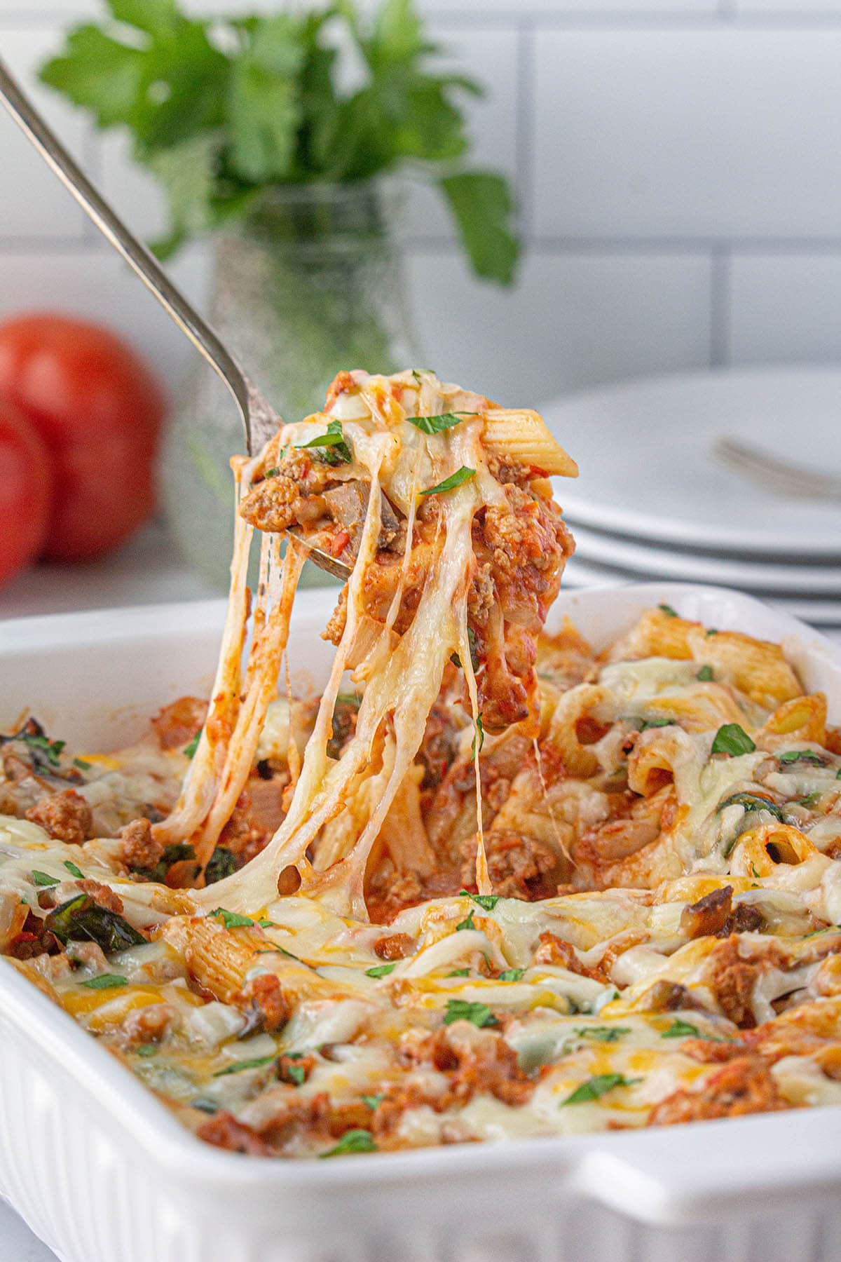 Baked casserole with a serving spoon taking a big scoop pasta.