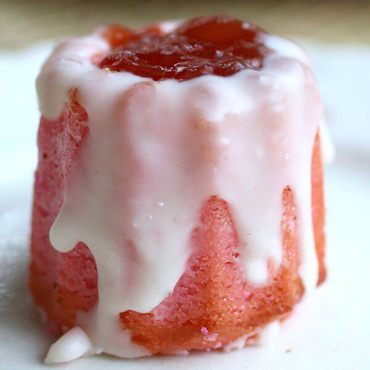 Pink velvet cupcakes on plate with a white drizzle glaze.