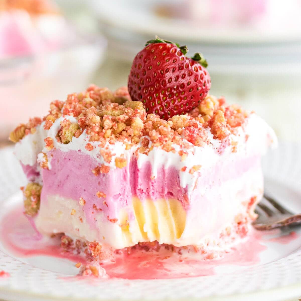 A slice of pink strawberry ice cream cake on a plate.