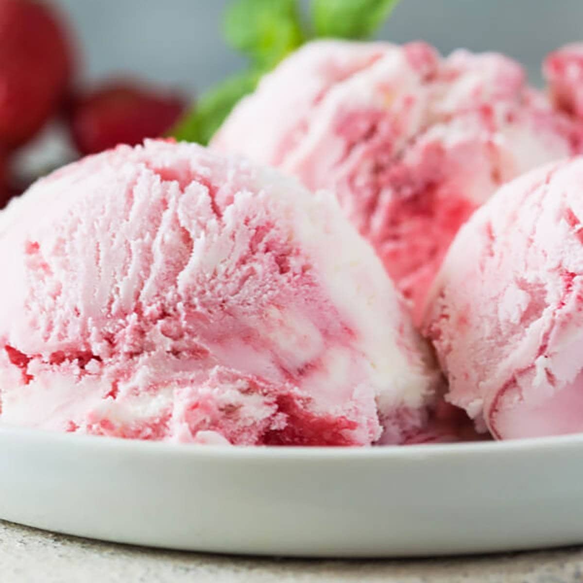 Scoops of strawberry ice cream in a shallow bowl.