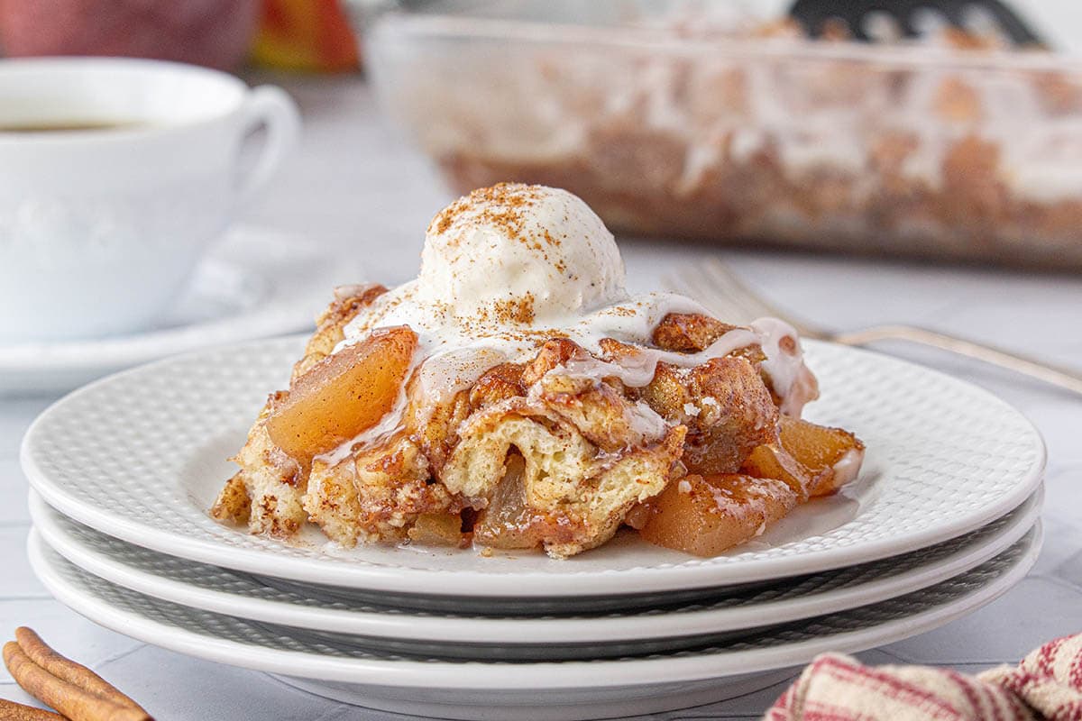 Apple cobbler on a plate topped with vanilla ice cream.