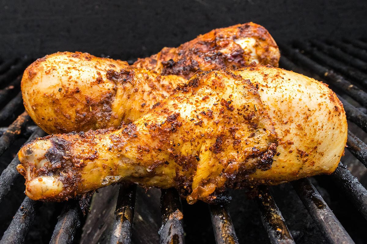 Chicken drumsticks on a grill being bbq'd.