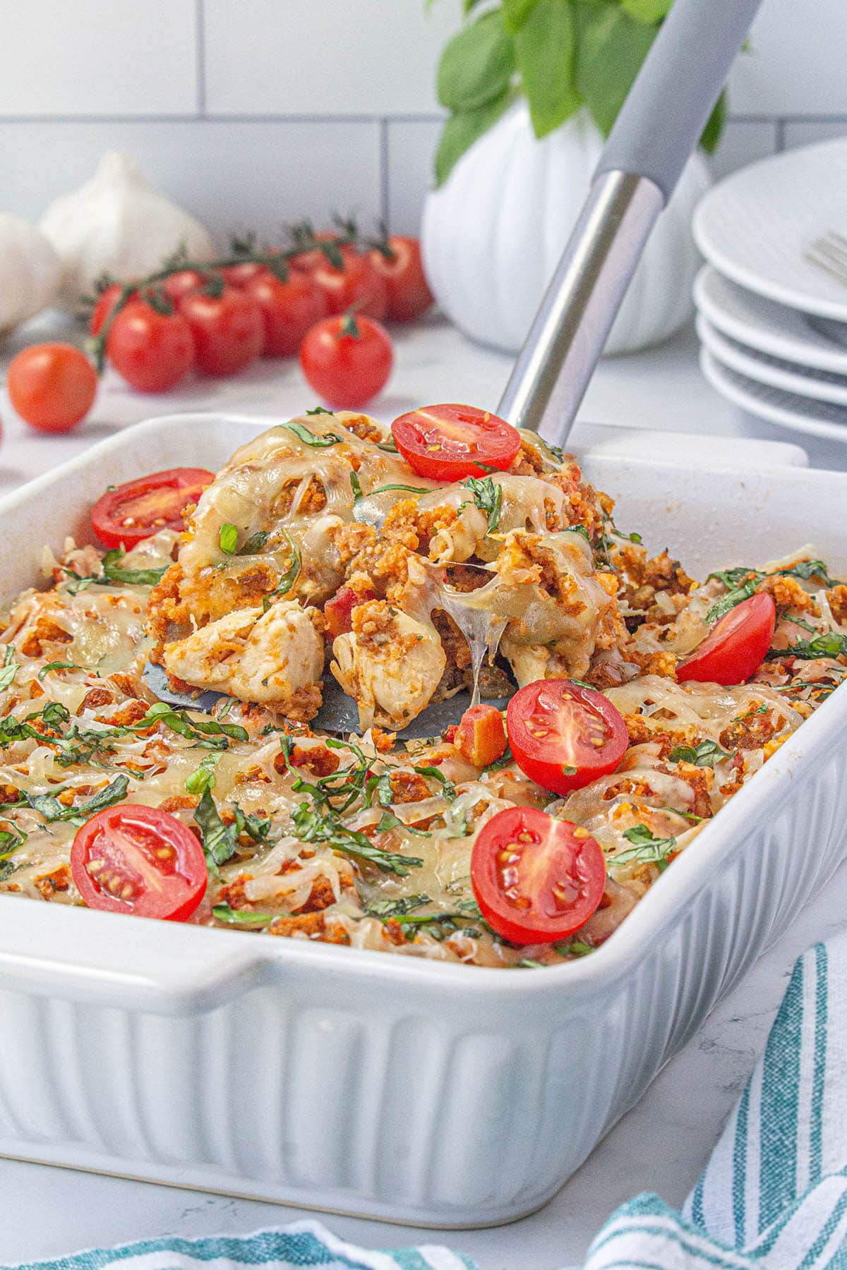 Chicken Bruschetta casserole in baking dish with spatula taking out a serving.