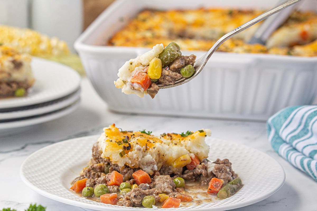 Shepherds pie on a plate with a fork scooping out a bite.