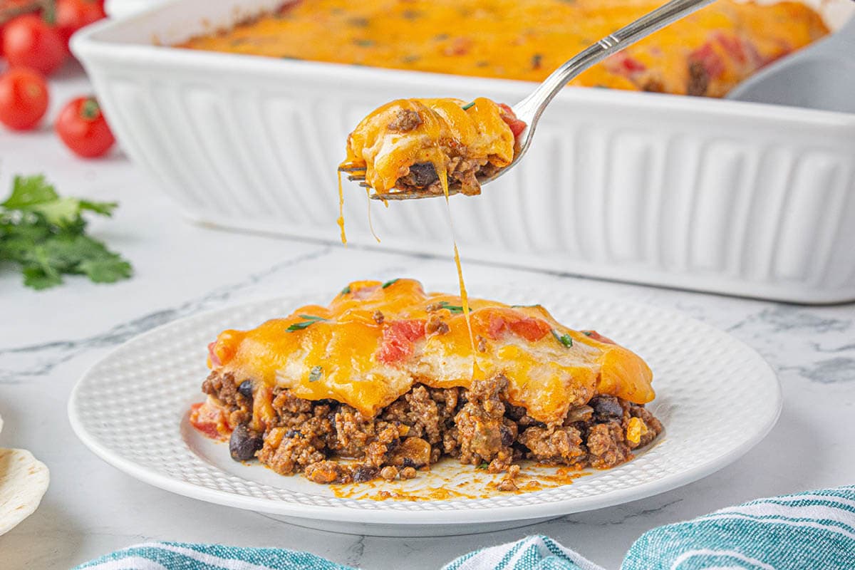 Ground beef casserole serving on a plate with a fork.