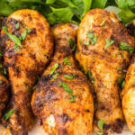 Grilled chicken legs on a platter garnished with chopped parsley.