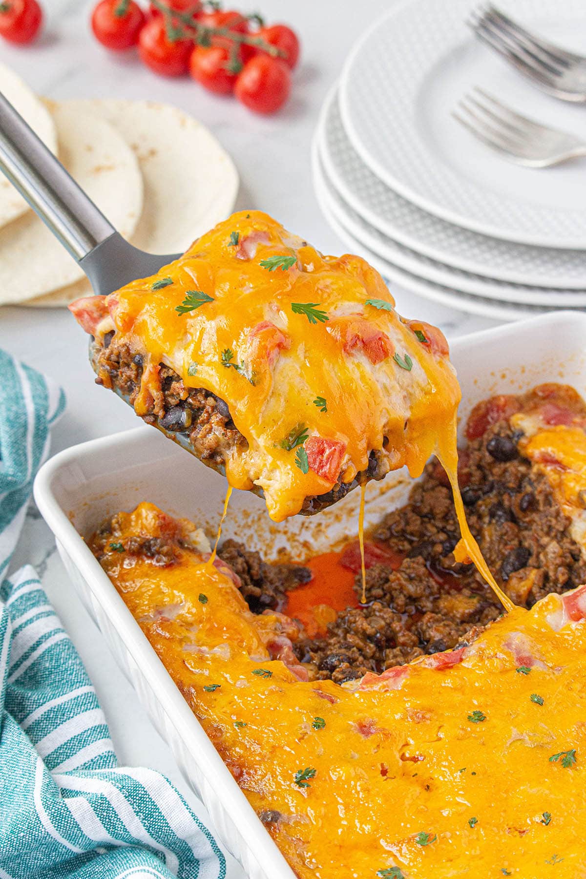 Cheesy Firecracker Casserole in baking dish with serving spatula taking out a serving.
