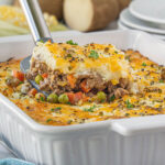 Shepherds pie casserole in a baking dish. There's a spatula dishing up a serving.