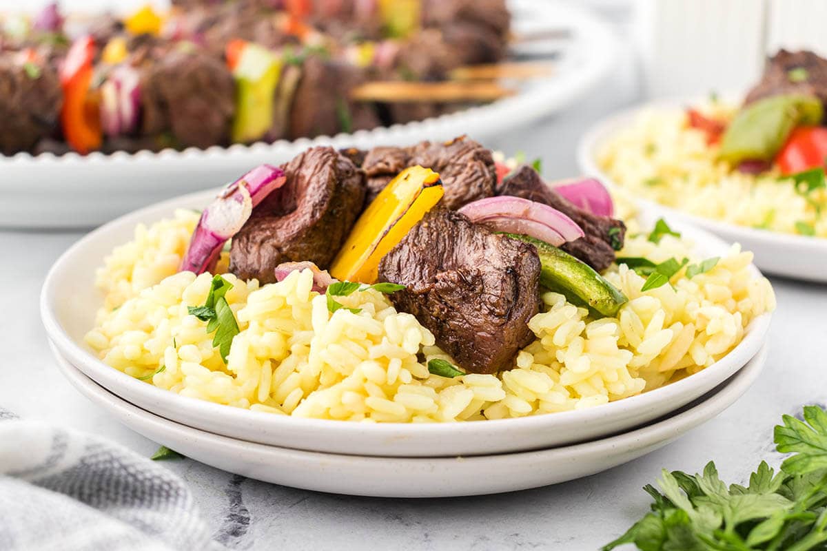 Steak kabobs over rice on a platter.