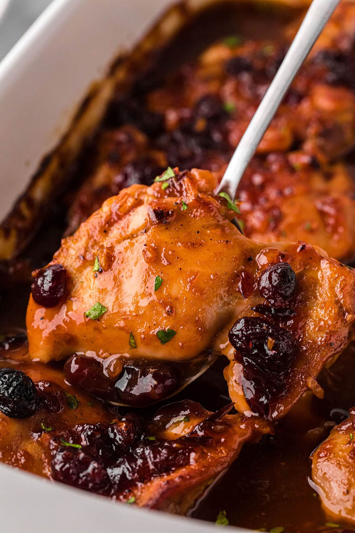 Catalina Cranberry Chicken in a baking dish with a serving spoon dishing up a piece.