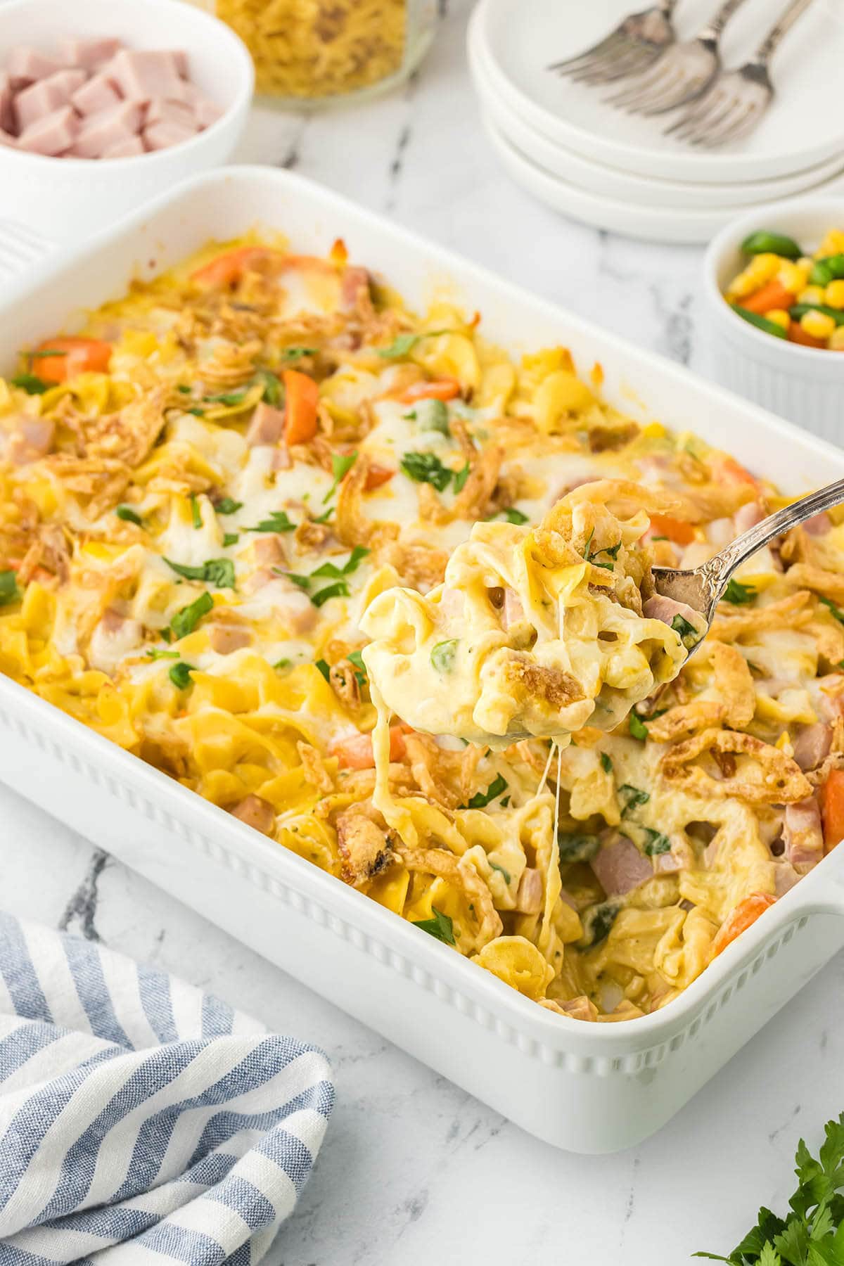 Casserole dish filled with ham and noodle bake. With a serving spoon.