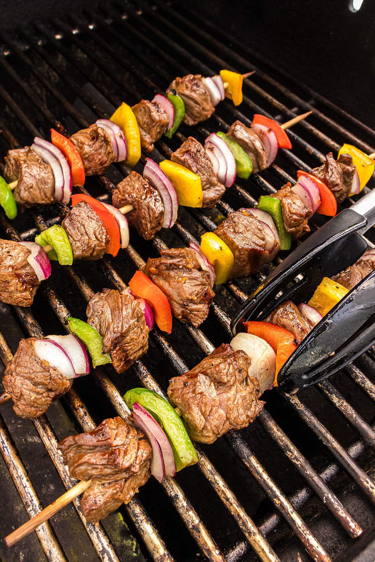 Kabobs being bbq's on a gas grill.