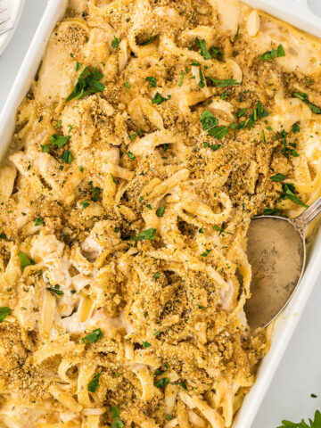 Chicken Alfredo Pasta in a baking dish wish a serving spoon.