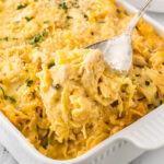 Baking dish filled with Chicken and Mushroom Pasta Bake, with a serving spoon.