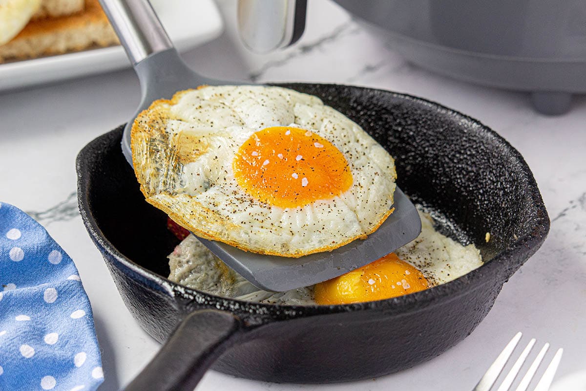 Air fryer fried eggs in skillet with a spatula.