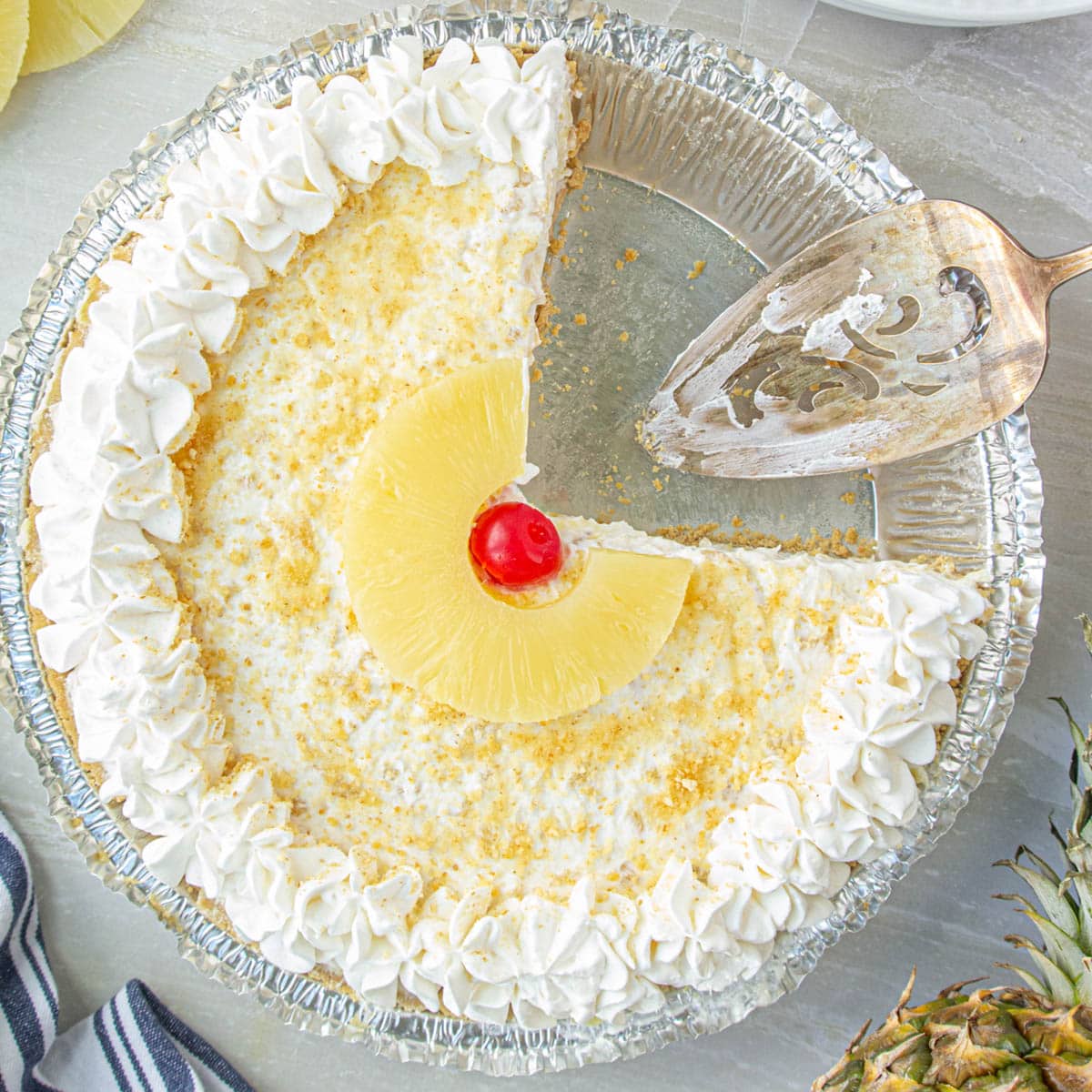 Overhead shot of No-Bake Pineapple Cream Cheese Pie with a serving spatula ready to dish up another slice.