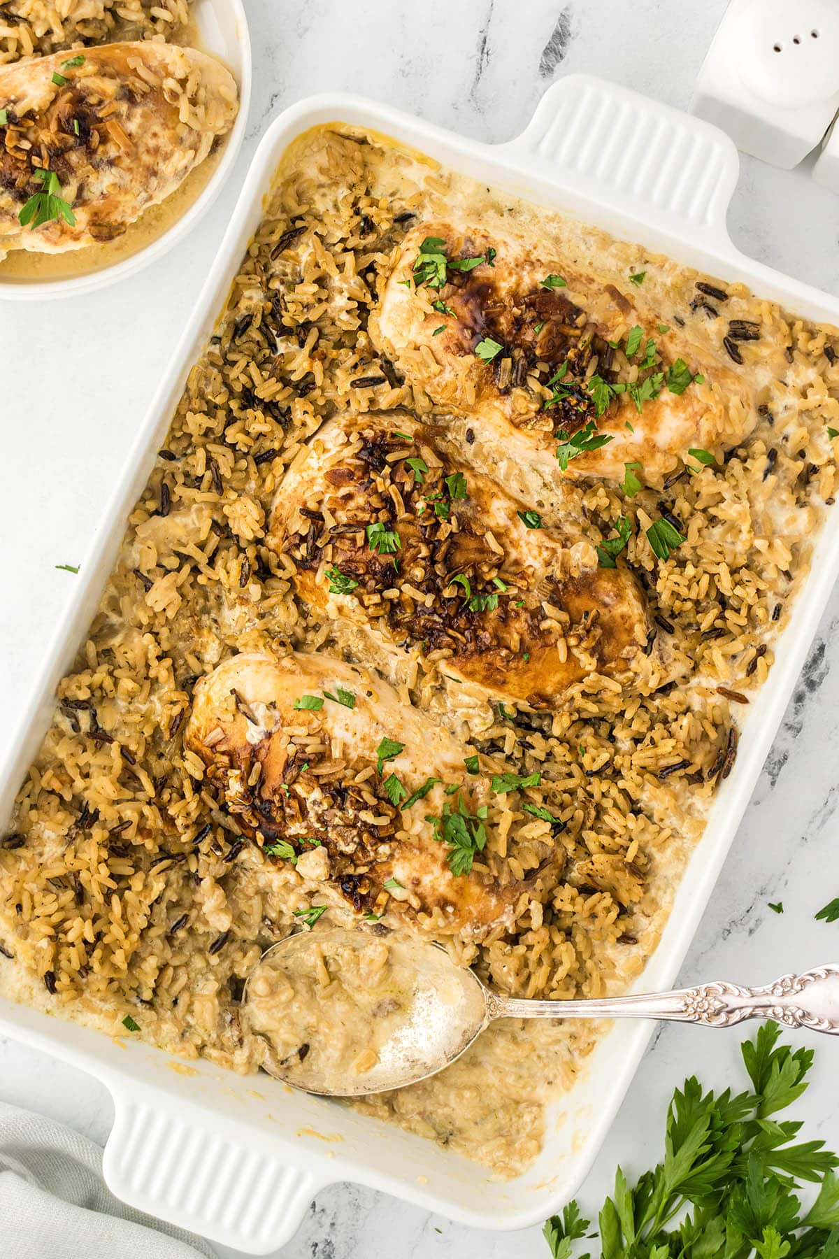 Chicken and rice bake in a casserole dish, with a serving spoon.